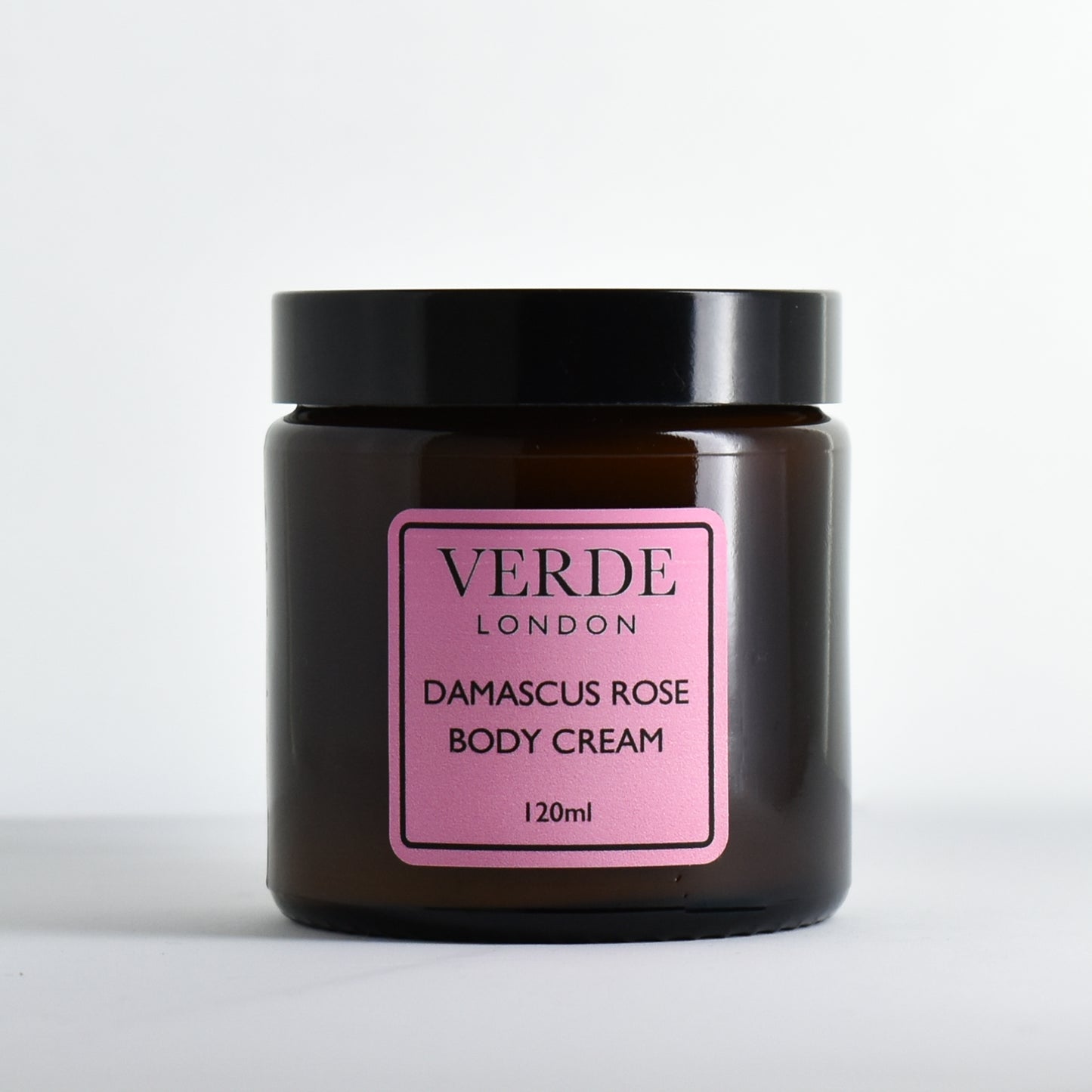 Amber glass jar of Damascus Rose Body Cream by Verde London with a pink label on a white background