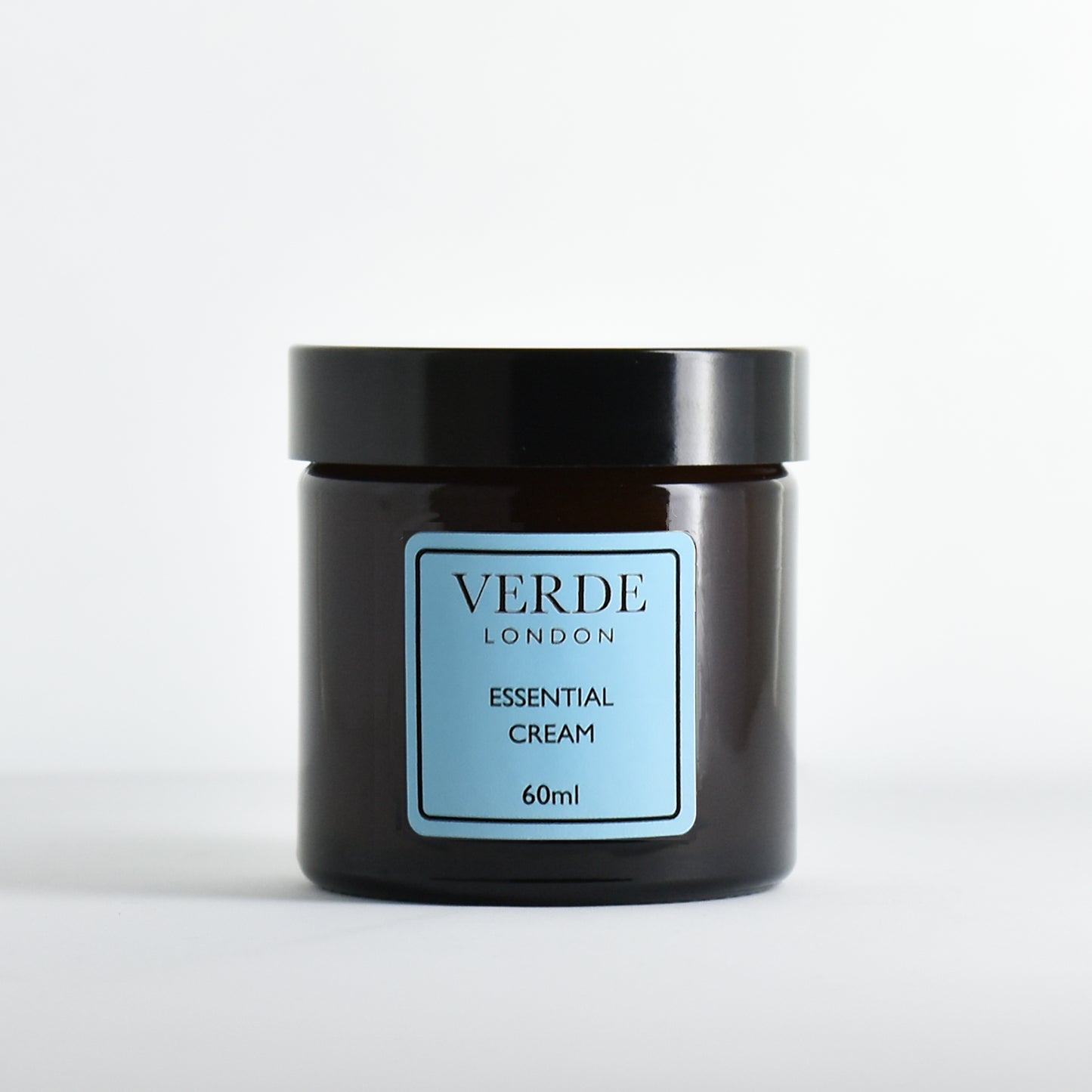 Amber glass jar of Verde London Essential Cream with a blue label on a white background