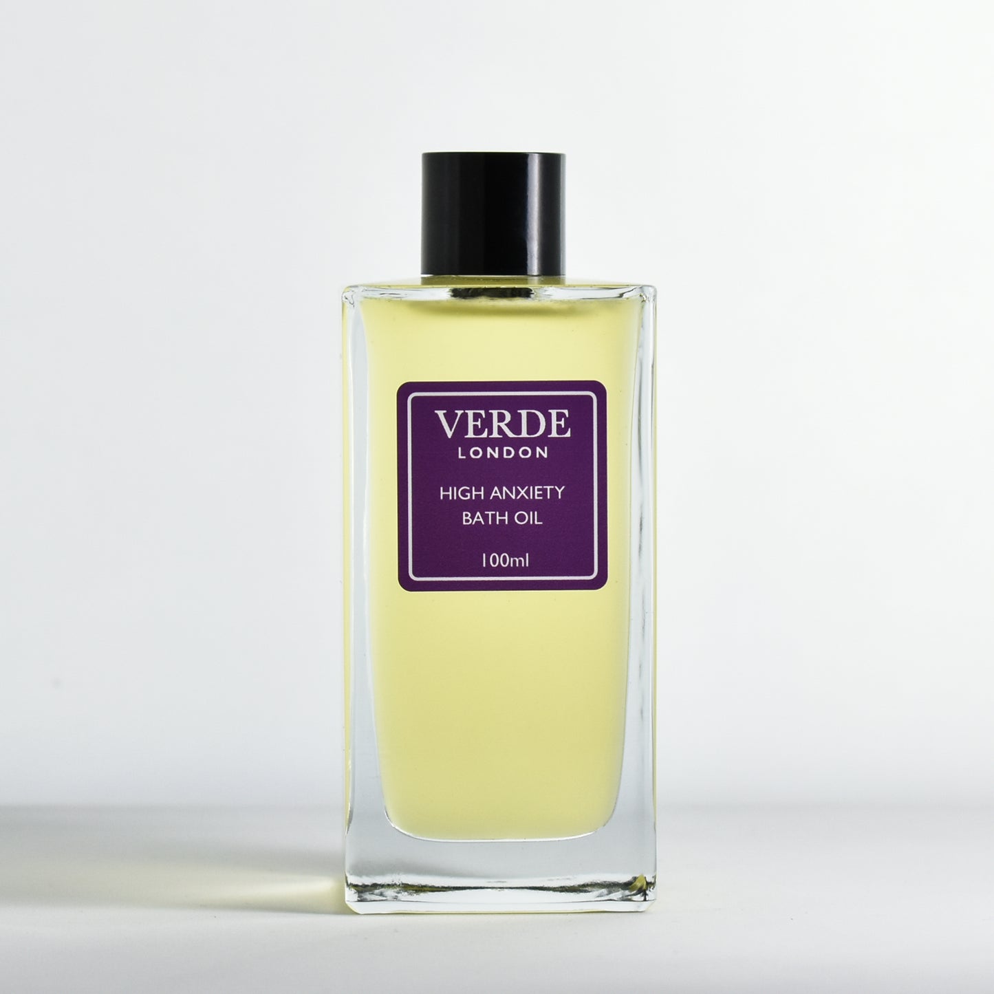 Bottle of 100ml 'High Anxiety Bath Oil' with a dark purple label by Verde London in a rectangular glass bottle on a white background