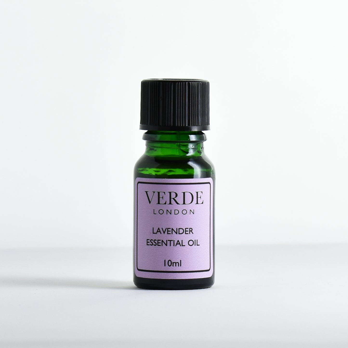 Green glass dropper bottle with purple label containing 'Lavender Essential Oil' by Verde London on a white background.