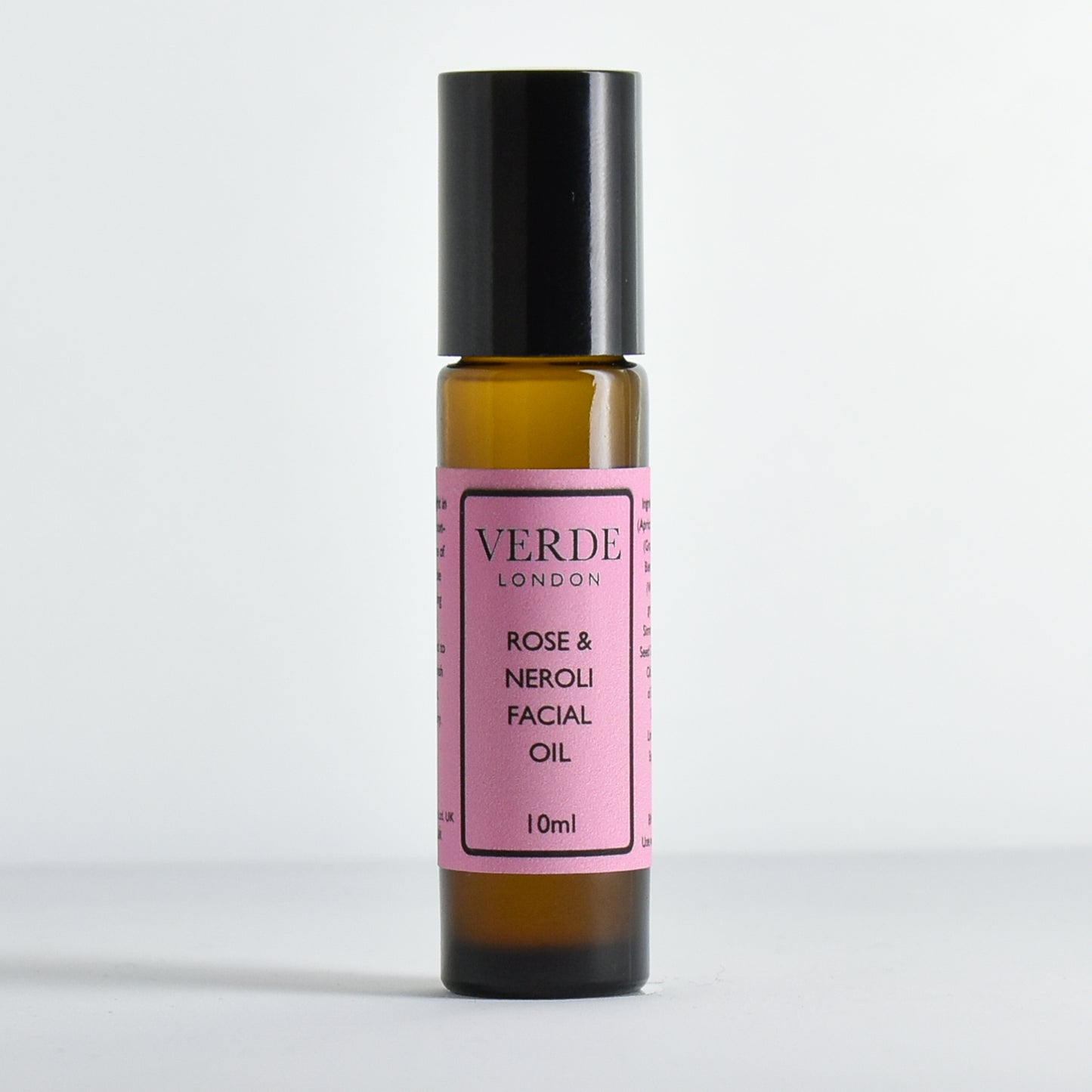 Amber bottle of Verde London Rose & Neroli Facial Oil with a pink label on a white background