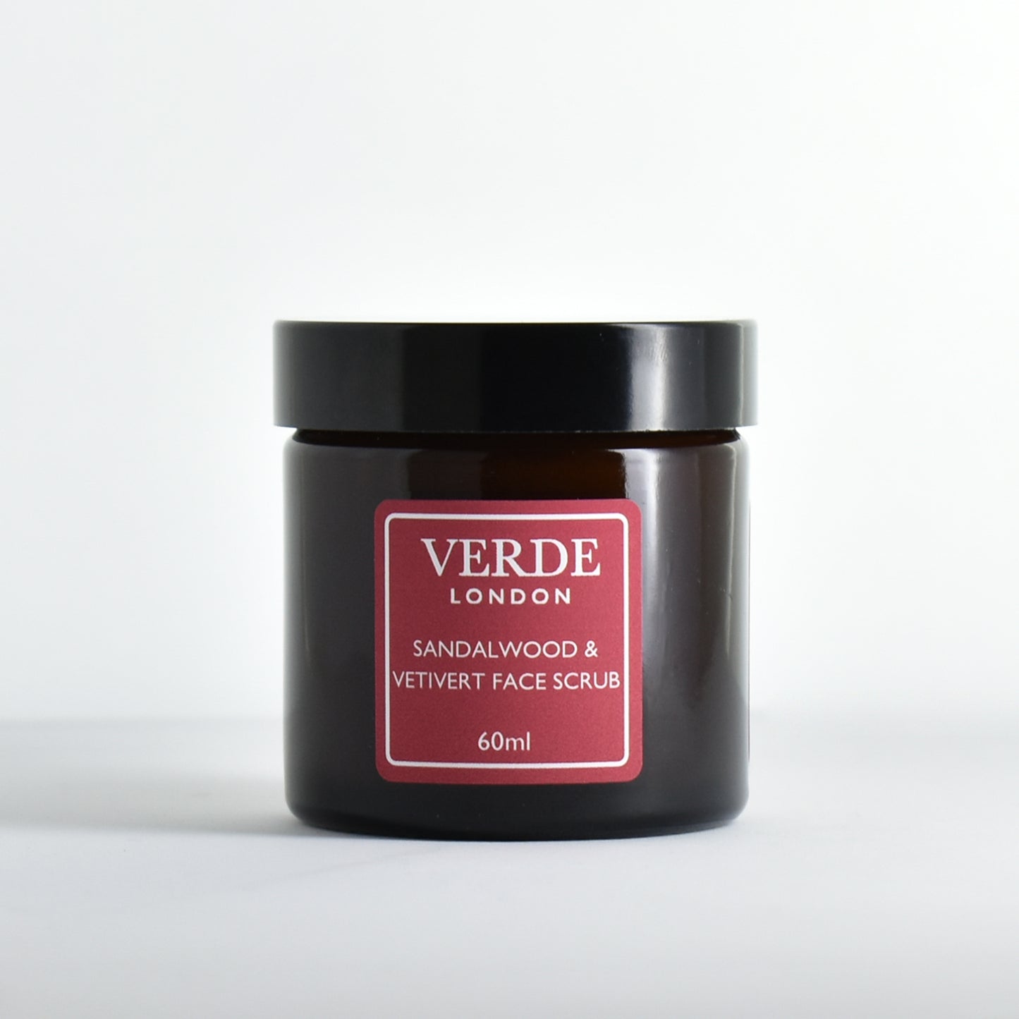 Amber glass jar of Verde London Sandalwood & Vetiver Face Scrub with a red label on a white background