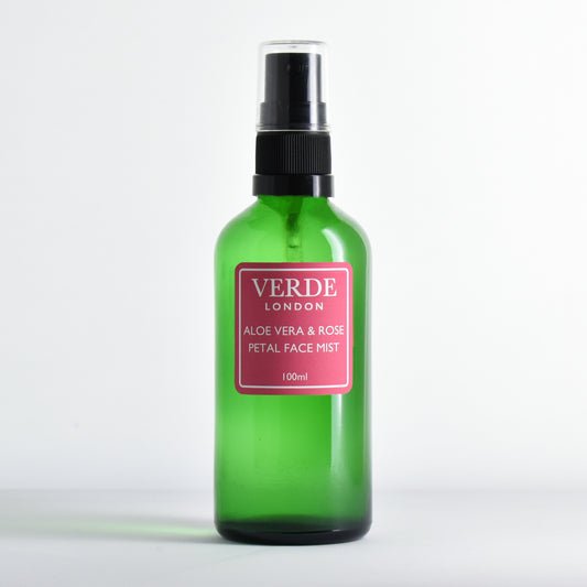 Green glass spray bottle of Aloe Vera and Rose Petal Face Mist by the brand Verde London with a pink label on a white bakground 