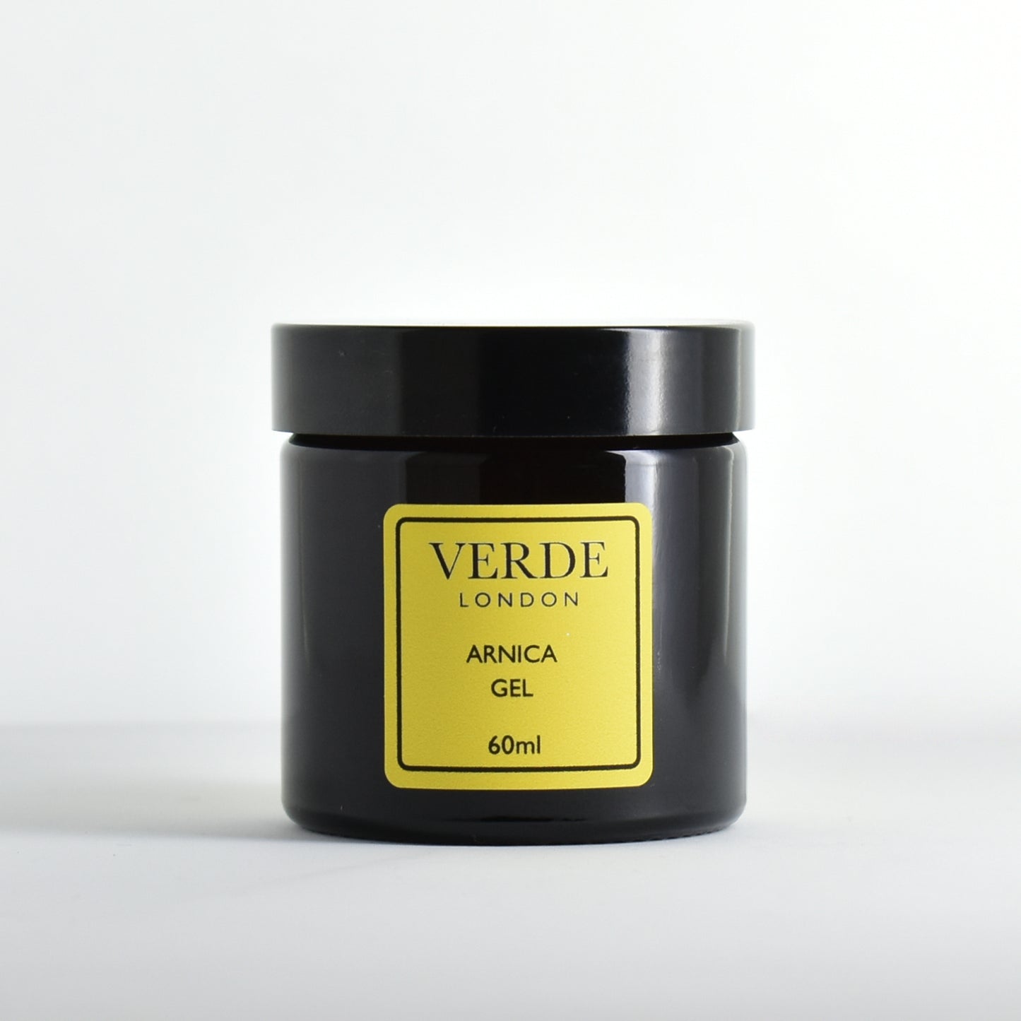 Amber glass jar of Arnica Gel by the brand Verde London with yellow label on a white background