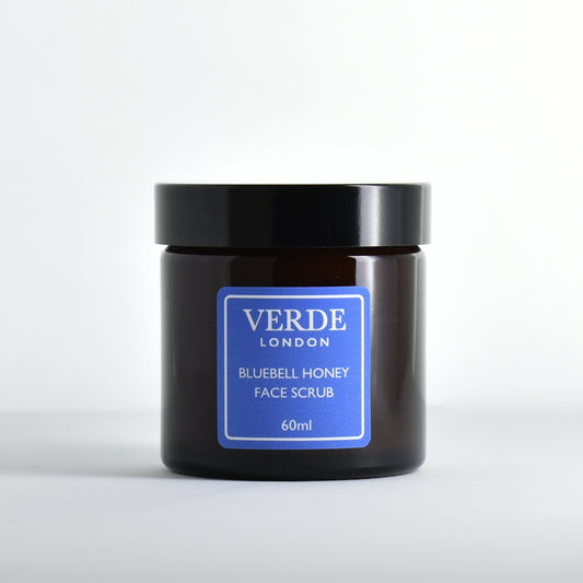 Amber glass jar of Verde London Bluebell Honey Face Scrub with a blue label on a white background