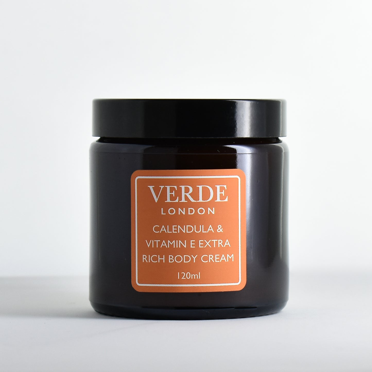 Amber glass jar of Verde London 'Calendula and Vitamin E eXtra Rich Body Cream' with an orange label on a white background