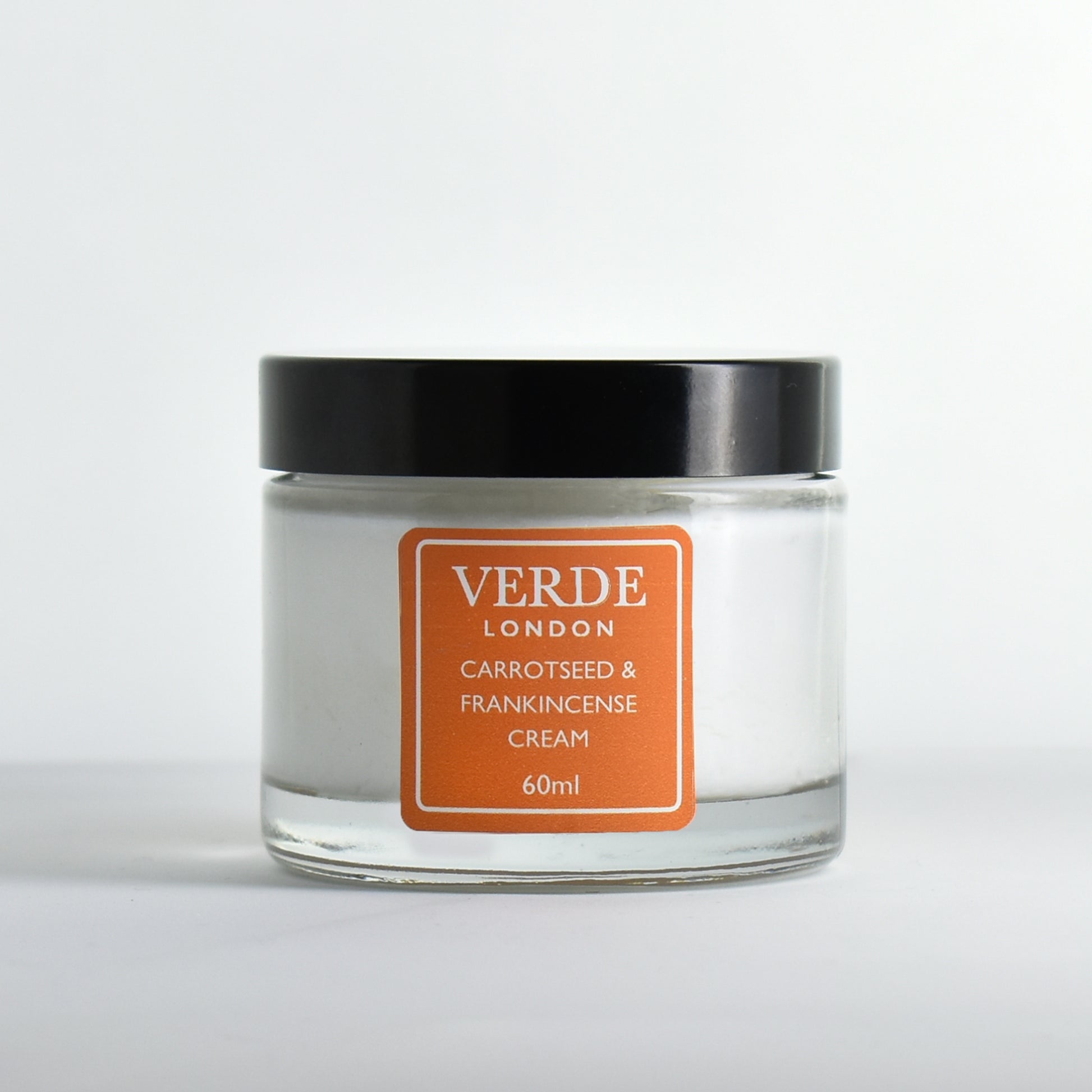Glass jar of Carrotseed and Frankincense cream with an orange label by the brand Verde London on a white background