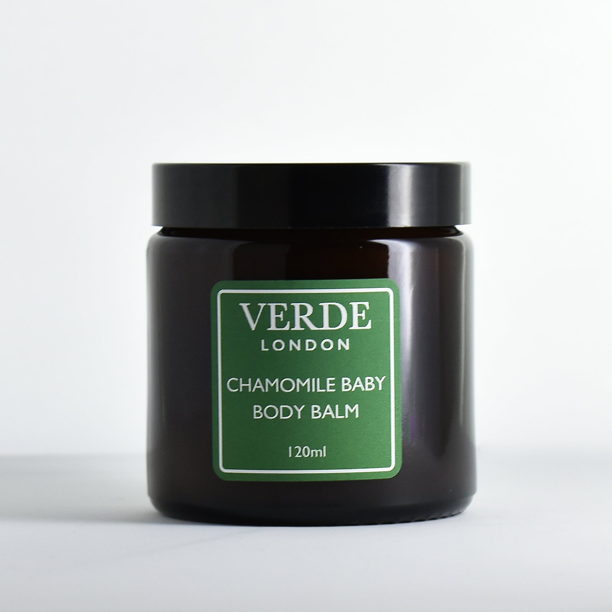 Amber glass jar of Chamomile Baby Body Balm by Verde London with a green label on a white background