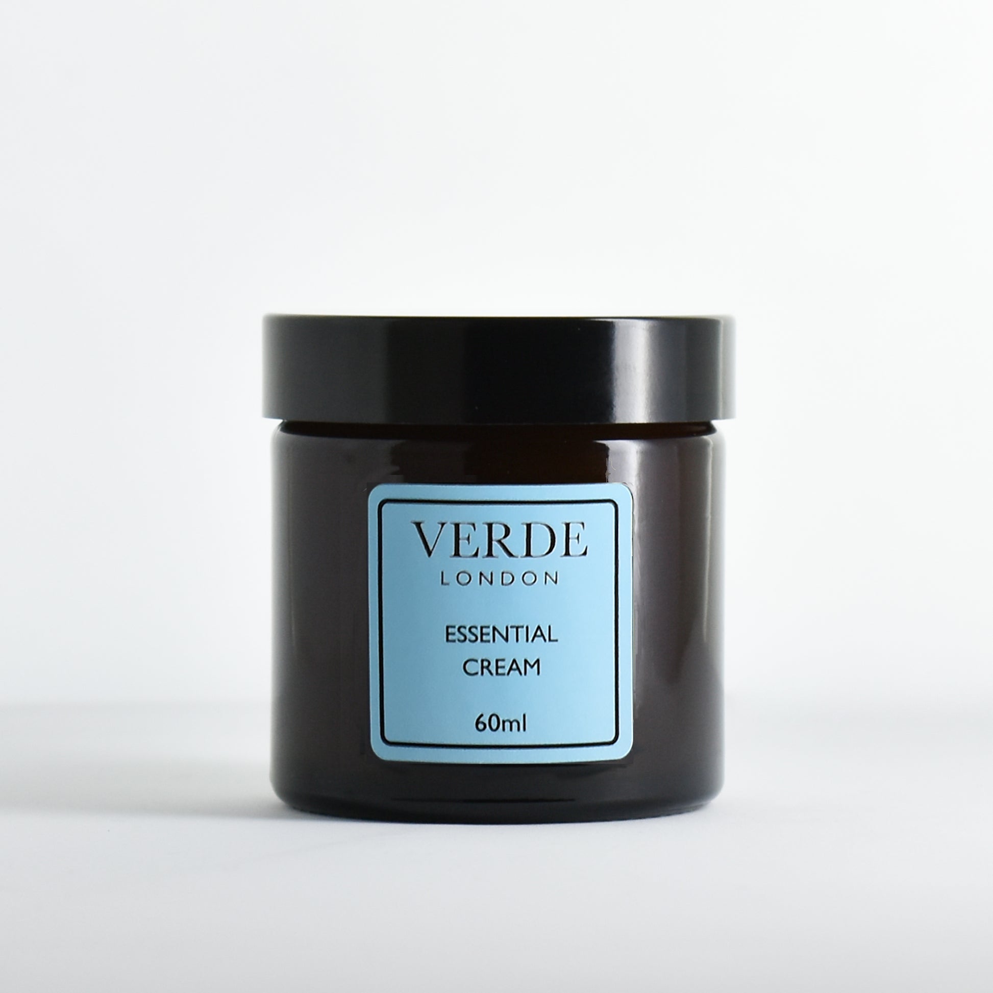 Amber glass jar of Verde London Essential Cream with a blue label on a white background