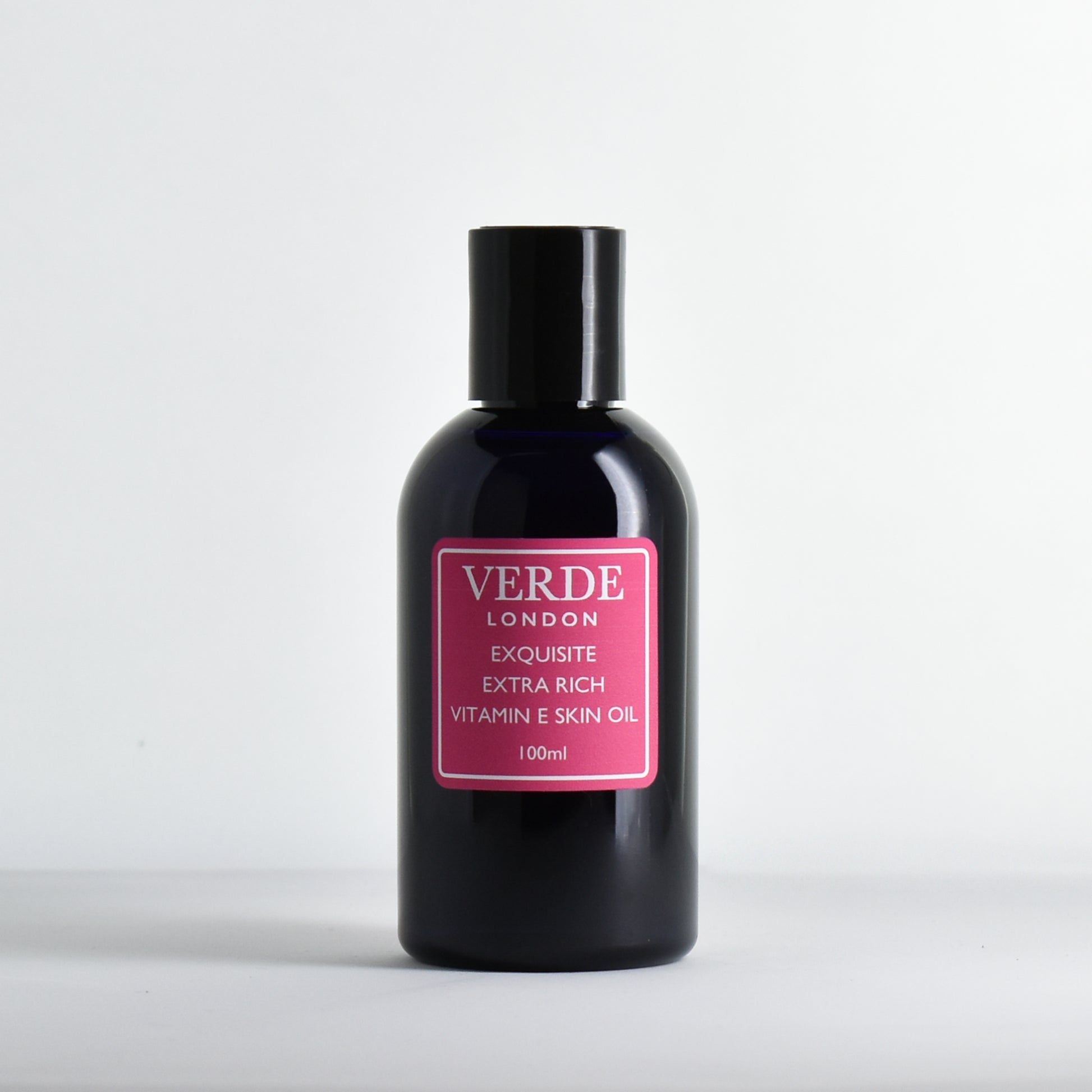 Blue 100ml bottle of Exquisite Exra Rich Vitamin E Skin Oil by the brand Verde London with a pink label on a white background