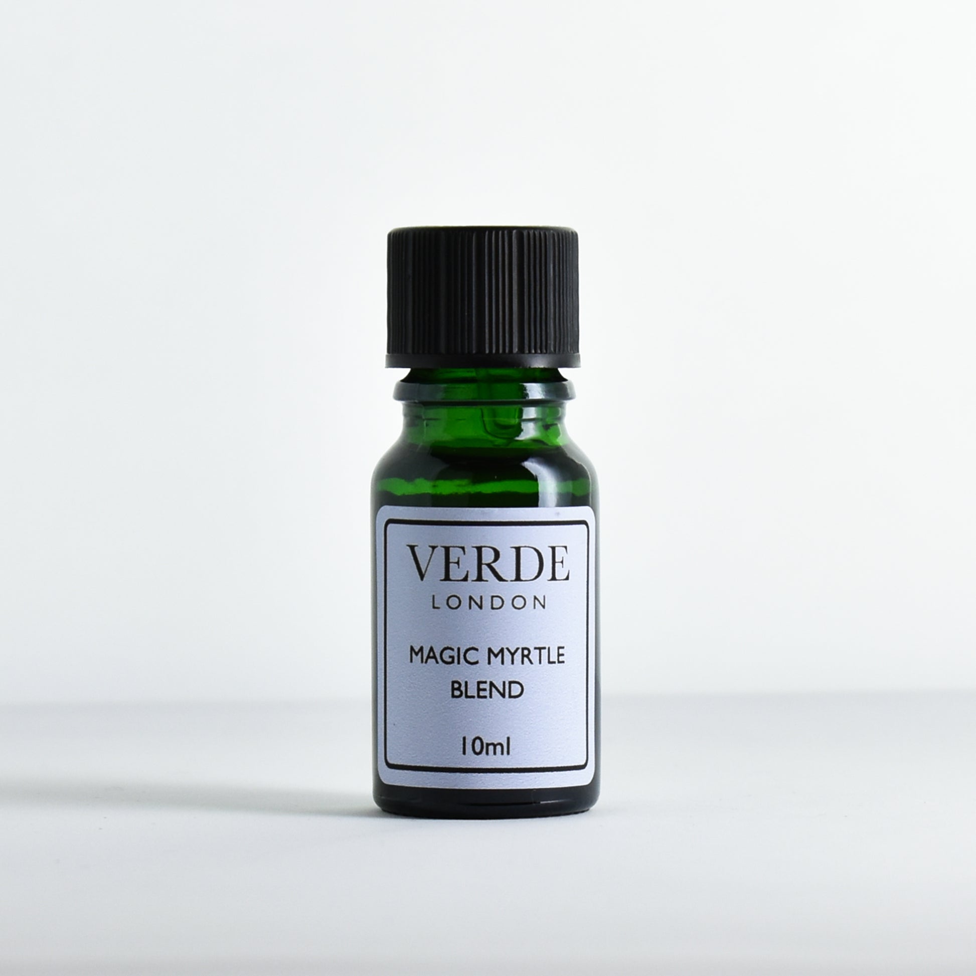 Green glass bottle of 'Magic Myrtle Blend' by Verde London with a pale blue label on a light gray background