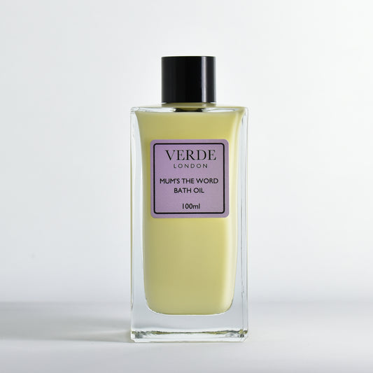 Bottle of Verde London 'mums the word' bath oil a yellowy millky colour with a pale purple label in a rectangular glass bottle on a white background