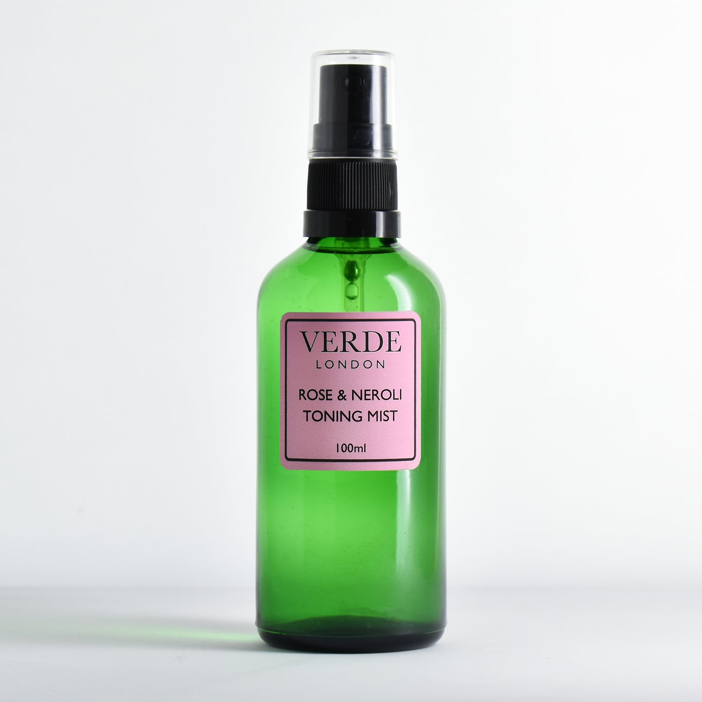 Green glass spray bottle of Rose and Neroli toning Mist by the brand Verde London with a pink label on a white background 