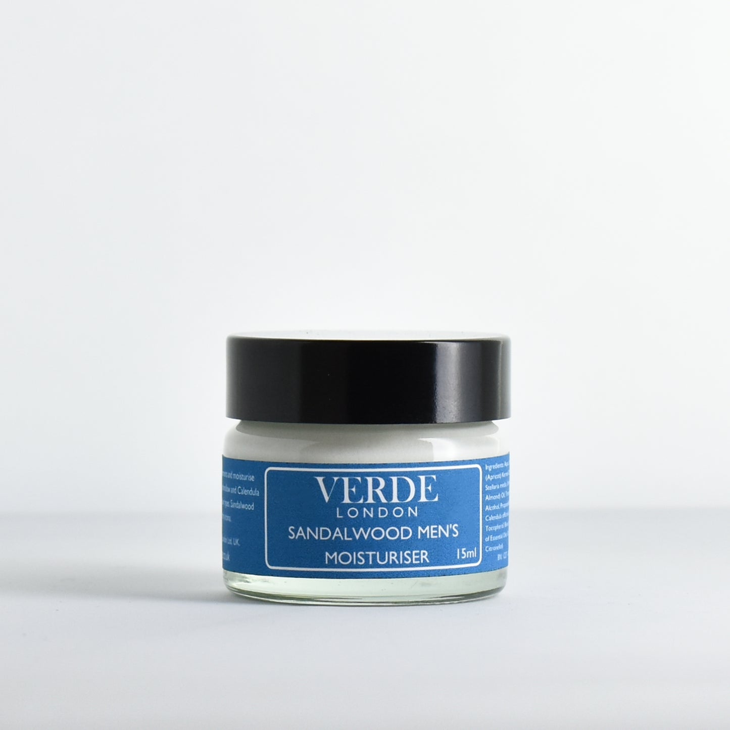 Glass jar of sandalwood men's moisturiser with a blue label by the brand Verde London on a white background