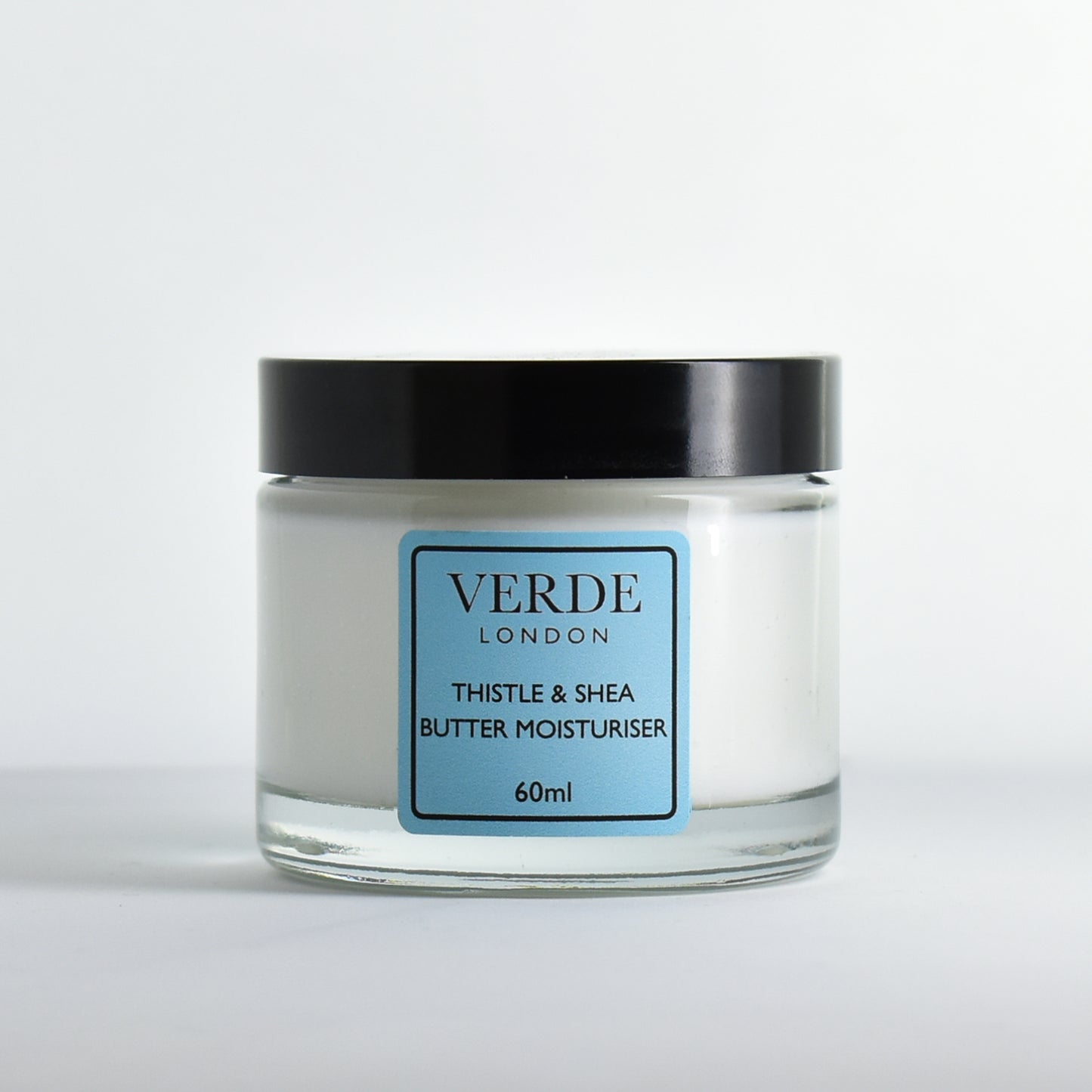 Glass jar of Verde London Thistle and Shea Butter Moisturiser with a blue label on a white background